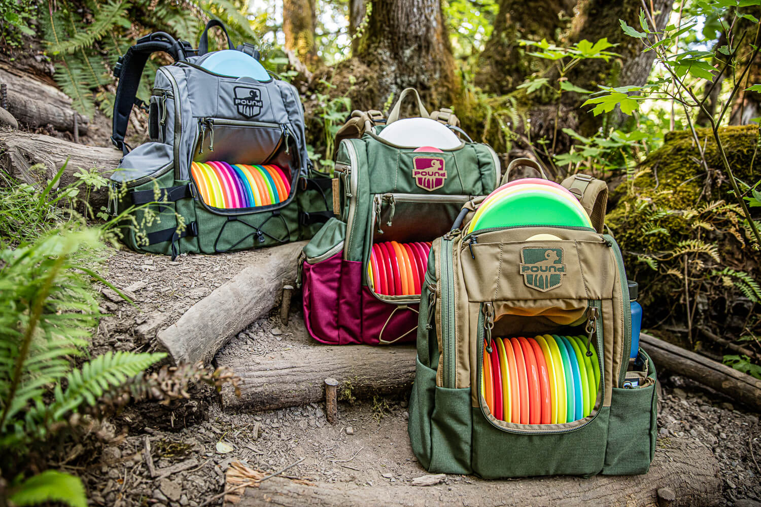 Three Pound disc golf bags sitting on a trail in the woods.